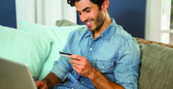 male holding credit card looking at laptop