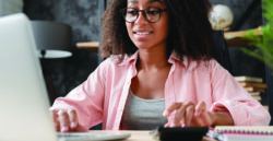 young woman at desk using laptop and calculator